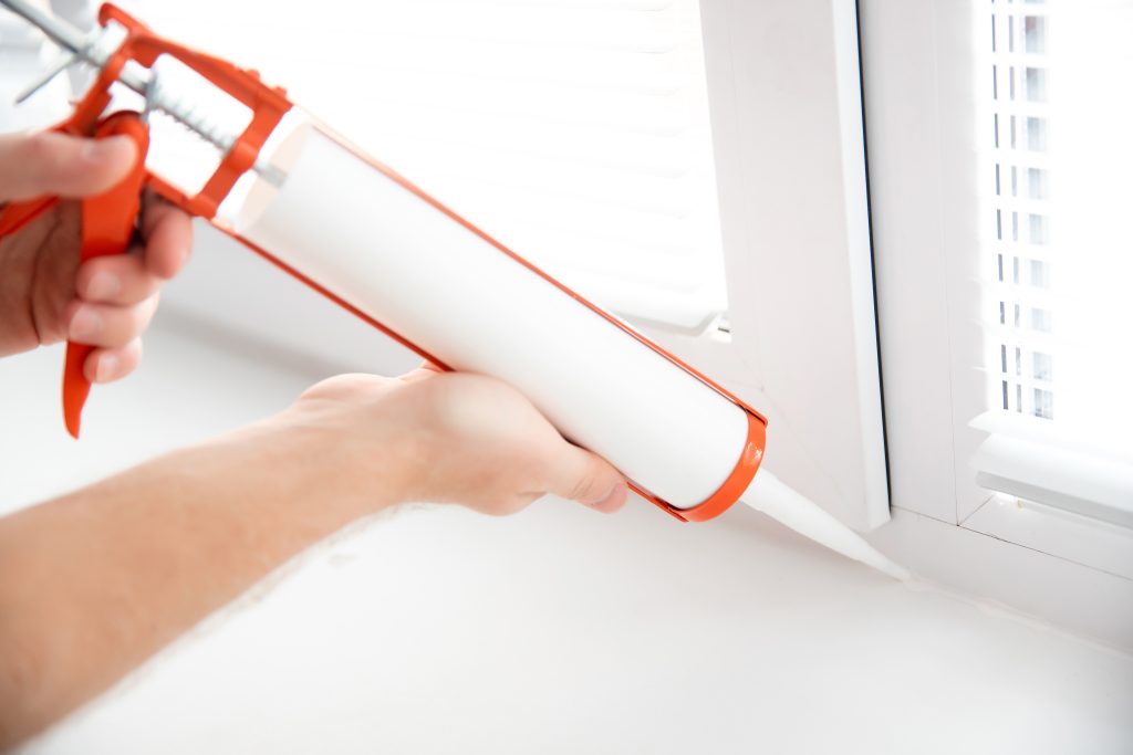 Construction worker use gun silicone tube for repairing and installing window in house