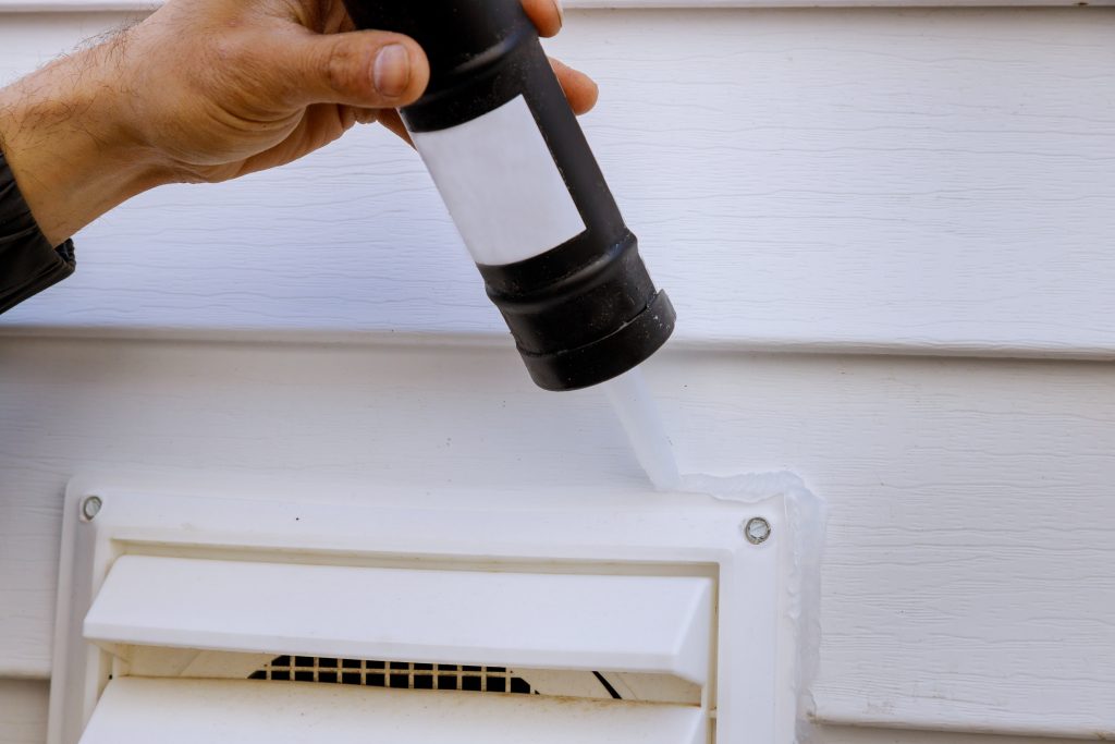 Applying silicone in installing side fan for laundry fan outside siding trim