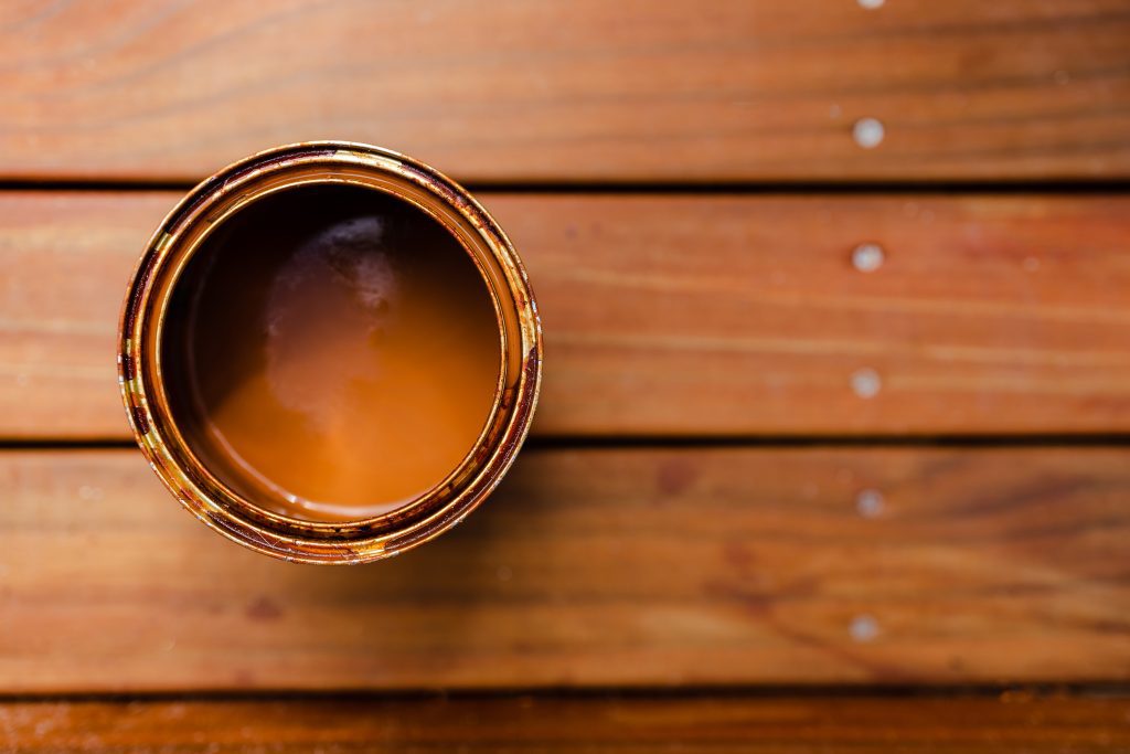 open pot of decking stain on top of outdoor wooden stairs