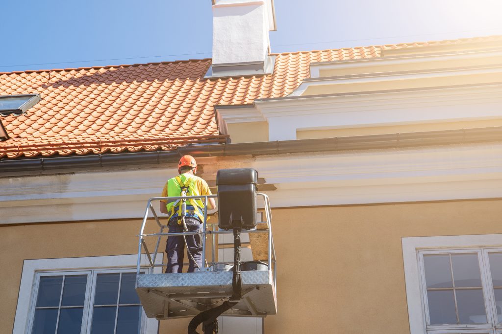 Worker repairs the facade of the building